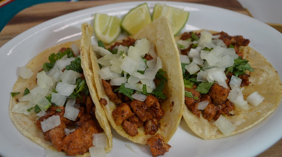 Tacos prepared with seasoned adobo meat, onion, cilantro and lime
